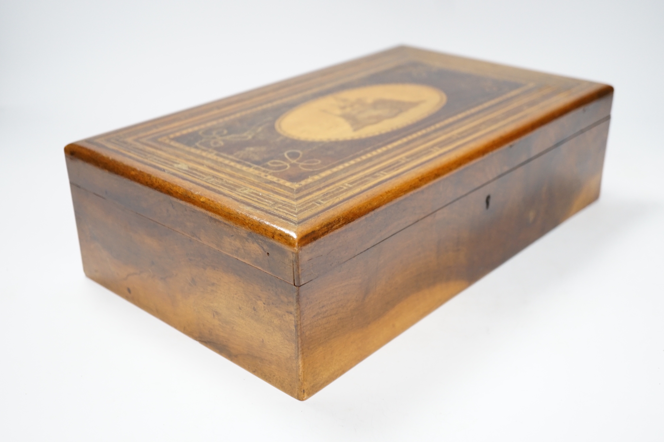 A late 19th century walnut sewing box, inlaid with a Napoleonic sea fort to a central cartouche on the lid and a fitted interior 33cm wide x10cm high